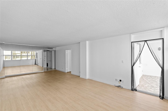 unfurnished living room with light wood-type flooring and a textured ceiling