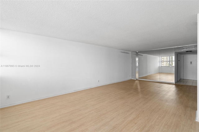 empty room with light hardwood / wood-style floors and a textured ceiling