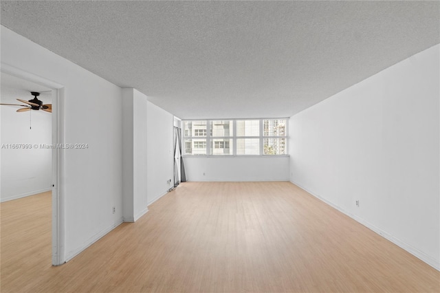 empty room featuring ceiling fan, light wood-type flooring, and a textured ceiling