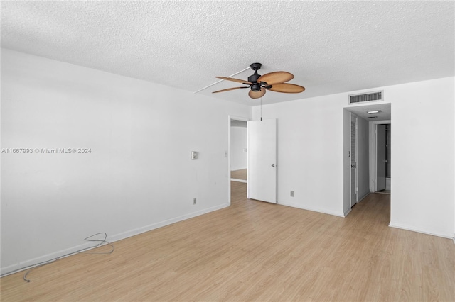 empty room featuring light wood-type flooring, ceiling fan, and a textured ceiling