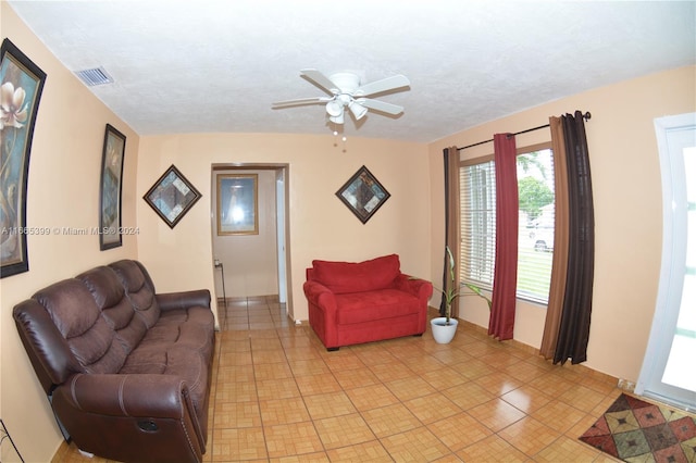 living room featuring light tile patterned flooring, a textured ceiling, and ceiling fan