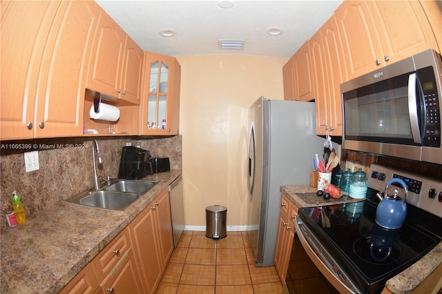 kitchen featuring tasteful backsplash, stainless steel appliances, sink, and light tile patterned floors