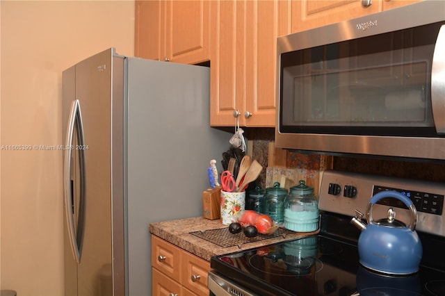 kitchen featuring appliances with stainless steel finishes, light stone countertops, and light brown cabinetry