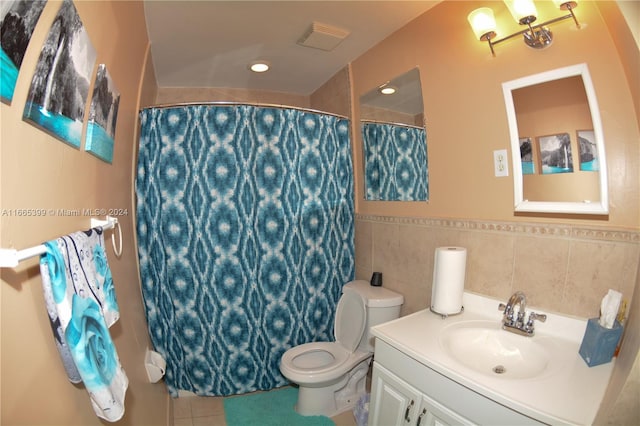 bathroom with tile patterned floors, toilet, vanity, curtained shower, and tile walls