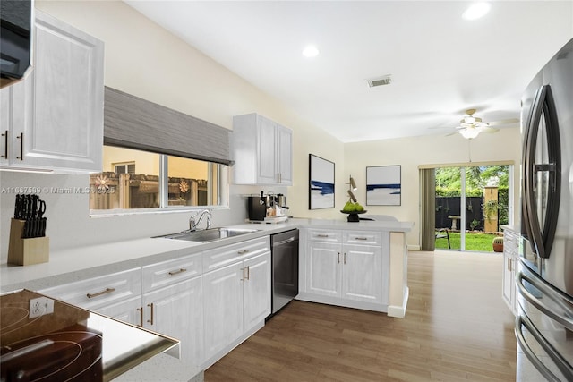 kitchen with kitchen peninsula, appliances with stainless steel finishes, white cabinetry, and sink