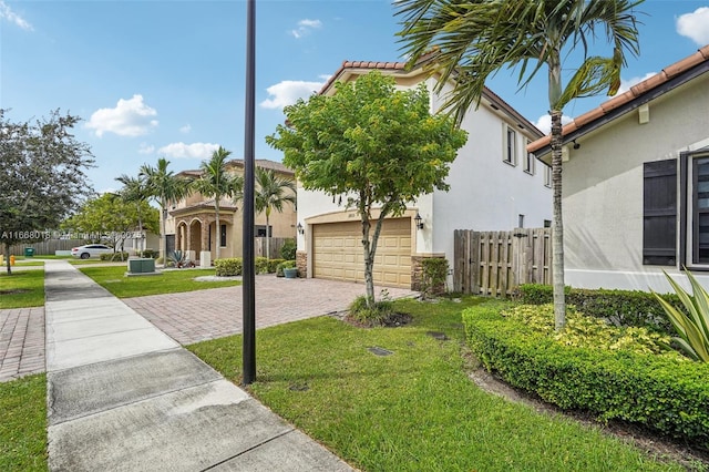 view of front facade with decorative driveway, a front yard, fence, and stucco siding