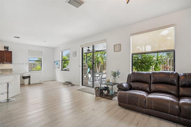 living area with light wood-style flooring, visible vents, and baseboards