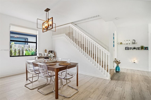 dining area with a notable chandelier, stairway, baseboards, and wood finished floors