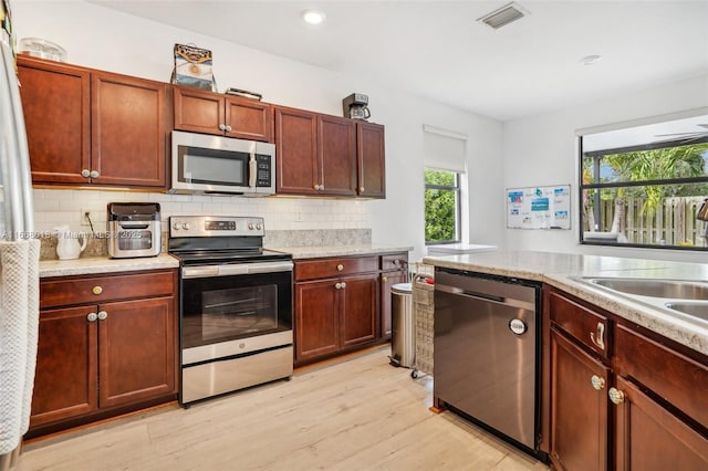 kitchen with light wood-style flooring, visible vents, light countertops, appliances with stainless steel finishes, and tasteful backsplash