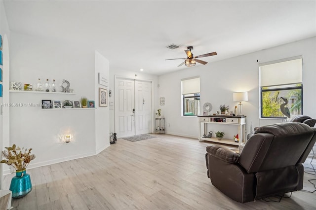 living area featuring light wood finished floors, baseboards, visible vents, and ceiling fan