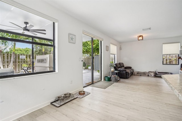 interior space featuring light wood-style flooring, baseboards, and a ceiling fan