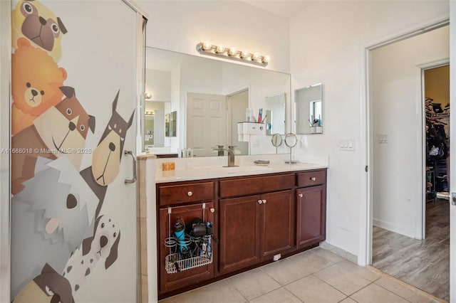 bathroom with vanity, baseboards, a walk in closet, and tile patterned floors