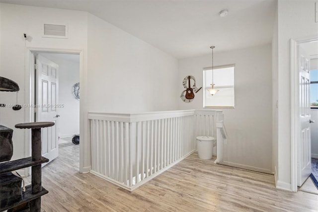 corridor featuring plenty of natural light, light wood-style flooring, visible vents, and an upstairs landing