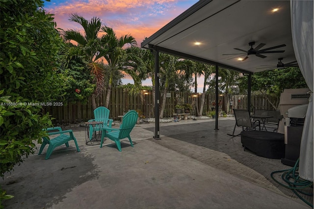 patio terrace at dusk featuring a fenced backyard and ceiling fan