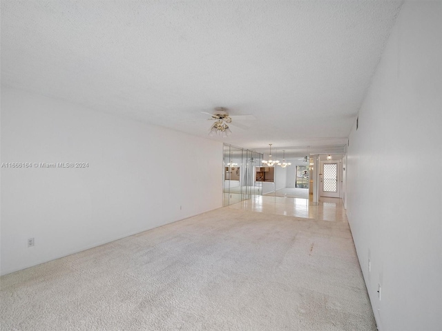 unfurnished living room with a textured ceiling, ceiling fan, and light colored carpet