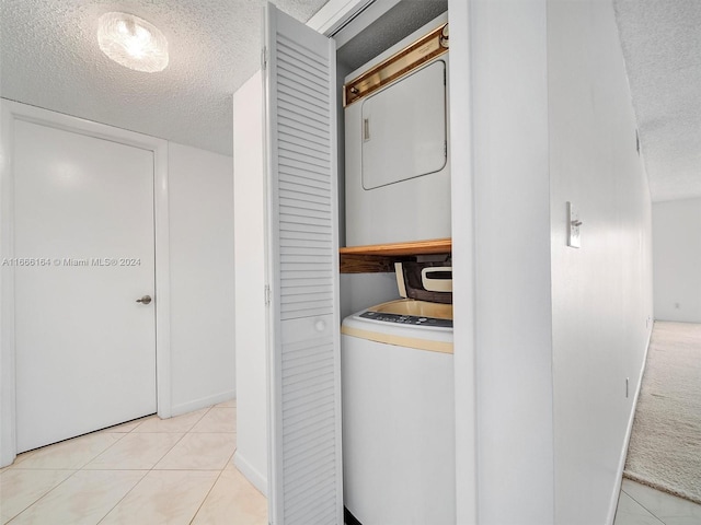 washroom with a textured ceiling, stacked washer and clothes dryer, and light tile patterned flooring