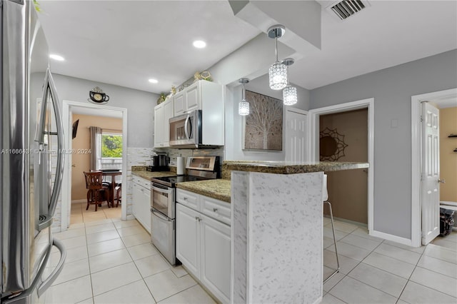 kitchen featuring white cabinets, hanging light fixtures, appliances with stainless steel finishes, a breakfast bar area, and light stone countertops