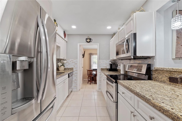 kitchen with white cabinets, light tile patterned flooring, appliances with stainless steel finishes, and hanging light fixtures