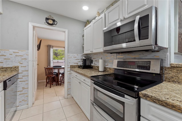 kitchen featuring white cabinets, appliances with stainless steel finishes, light tile patterned floors, and dark stone counters