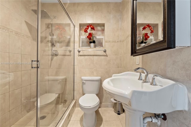 bathroom with tile walls, an enclosed shower, sink, tile patterned floors, and toilet