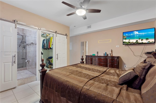 bedroom with a barn door, connected bathroom, light tile patterned floors, a closet, and ceiling fan