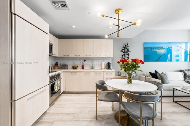 kitchen featuring light wood-type flooring, sink, decorative backsplash, stainless steel appliances, and an inviting chandelier