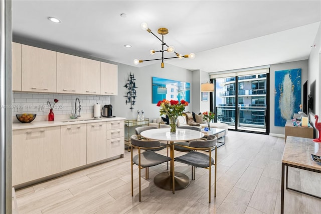 kitchen featuring backsplash, light wood-type flooring, decorative light fixtures, sink, and a notable chandelier