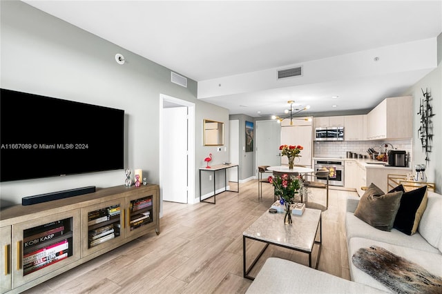 living room with light hardwood / wood-style flooring, a notable chandelier, and sink