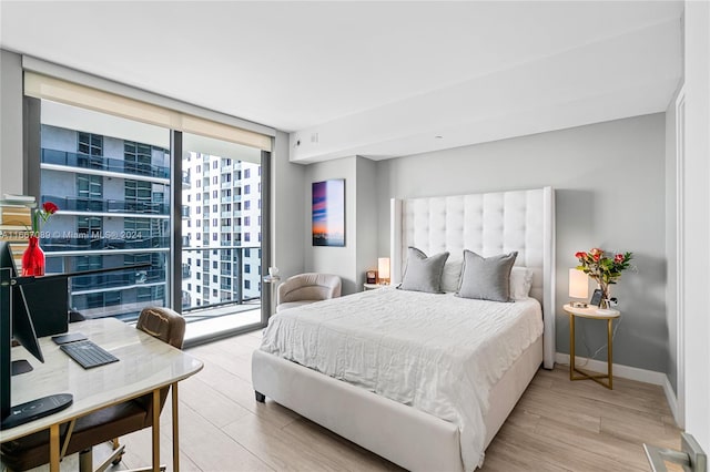 bedroom featuring light hardwood / wood-style floors, a wall of windows, and access to exterior