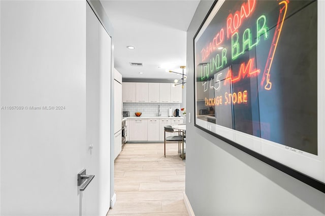 corridor with light hardwood / wood-style flooring and sink