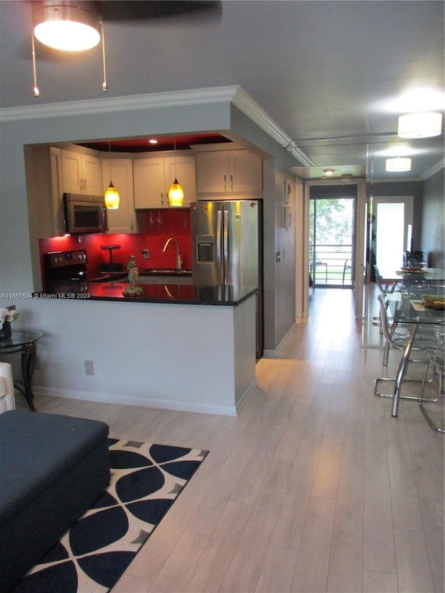 kitchen with pendant lighting, stainless steel appliances, light wood-type flooring, and crown molding