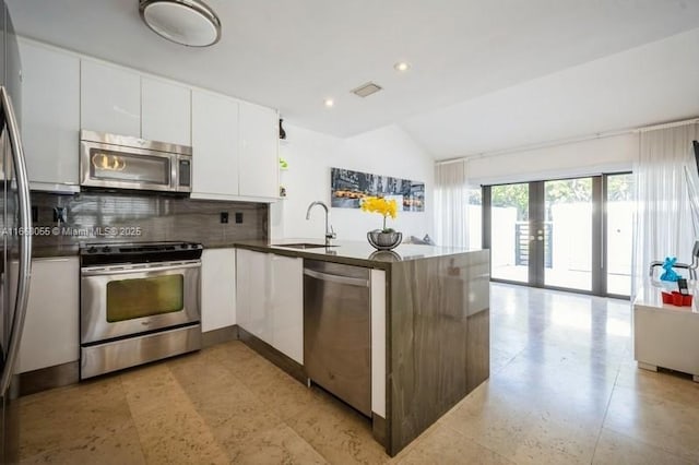21216 Harbor Way Unit 153-15, Aventura, FL 33180 - kitchen featuring a sink, stainless steel appliances, backsplash, a peninsula, and lofted ceiling
