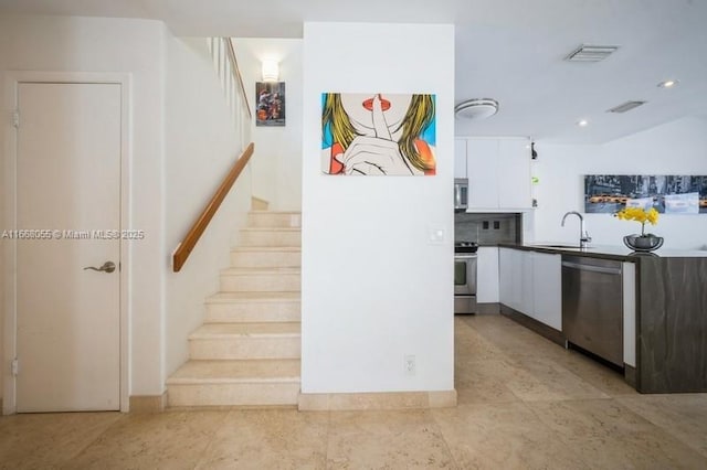 kitchen featuring appliances with stainless steel finishes, white cabinets, a sink, and visible vents