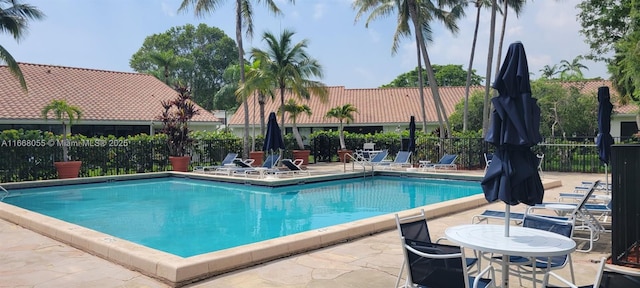 community pool with a patio and fence