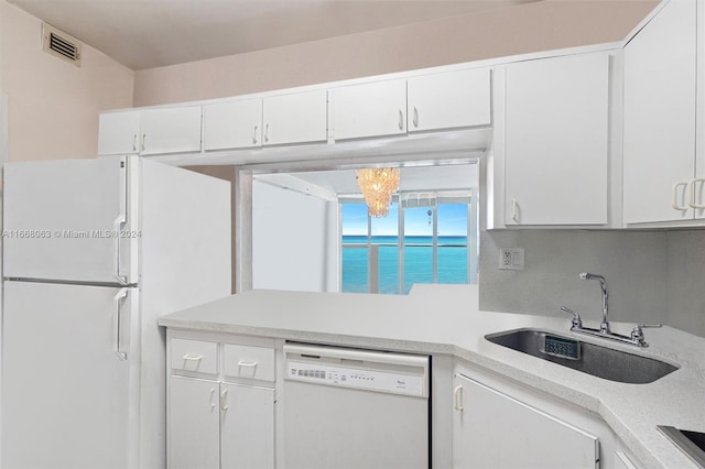 kitchen with a chandelier, sink, white cabinetry, a water view, and white appliances