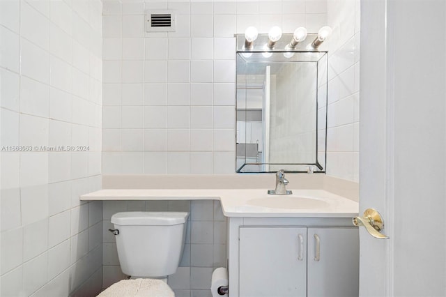 bathroom with tile walls, vanity, and toilet