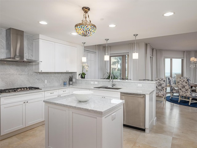 kitchen with sink, a kitchen island, wall chimney exhaust hood, white cabinetry, and stainless steel appliances