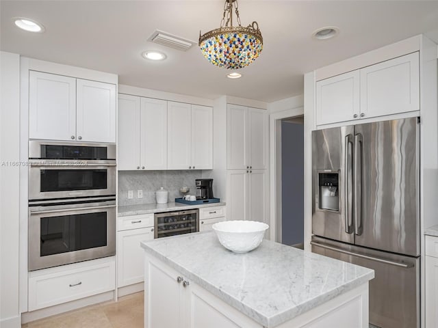 kitchen with appliances with stainless steel finishes, white cabinetry, beverage cooler, and pendant lighting