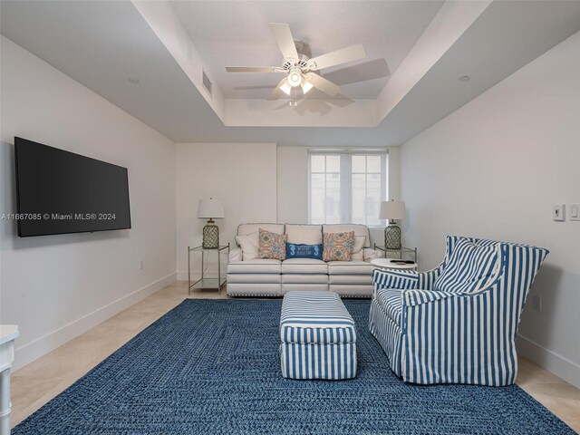 living room with a raised ceiling and ceiling fan