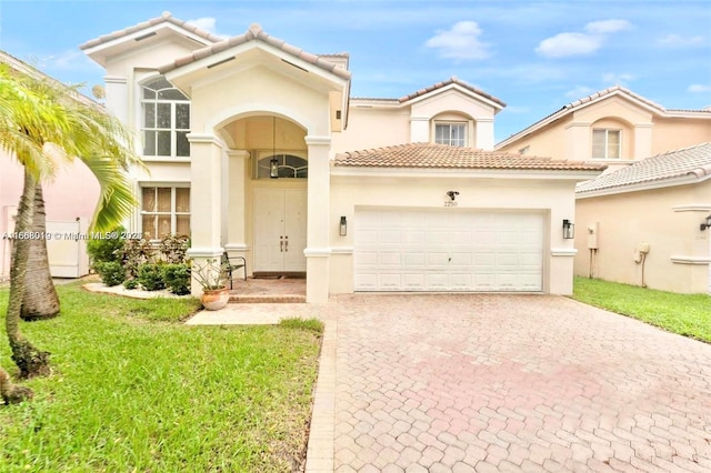 mediterranean / spanish-style house featuring decorative driveway, stucco siding, a front yard, a garage, and a tiled roof