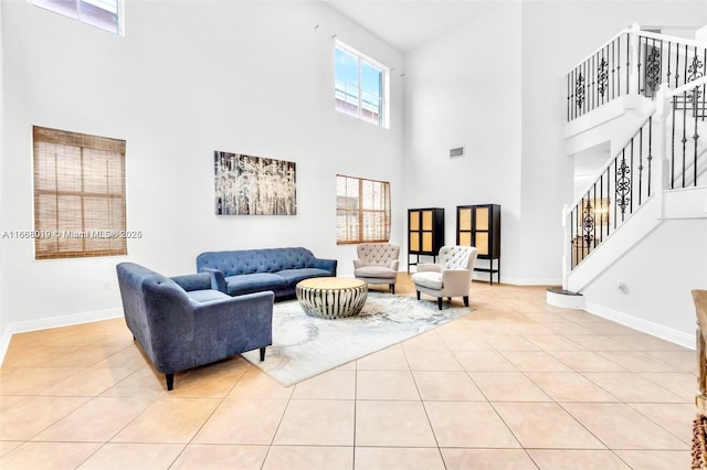 living area featuring light tile patterned flooring, stairway, and baseboards