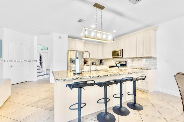 kitchen featuring a spacious island, stainless steel appliances, a breakfast bar, light stone countertops, and pendant lighting