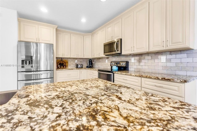 kitchen featuring light stone counters, backsplash, wood-type flooring, cream cabinetry, and stainless steel appliances