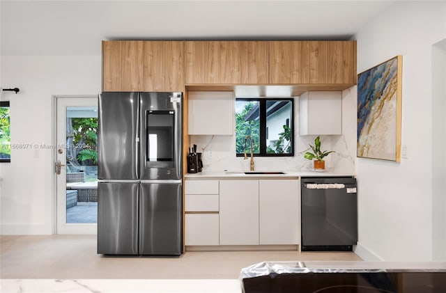 kitchen with a healthy amount of sunlight, stainless steel fridge, black dishwasher, and white cabinets