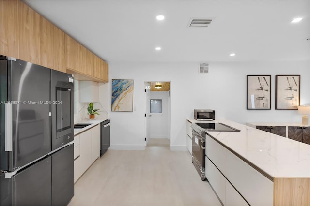 kitchen featuring white cabinetry, light stone counters, tasteful backsplash, stainless steel appliances, and light hardwood / wood-style flooring