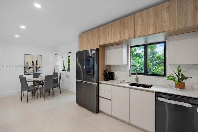 kitchen featuring stainless steel appliances, white cabinetry, sink, and backsplash