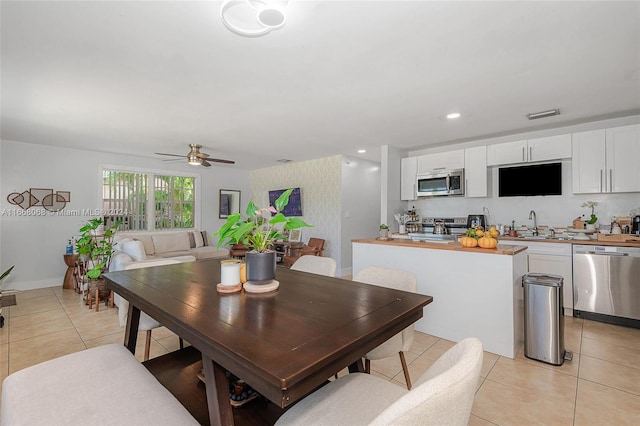 dining space featuring ceiling fan, light tile patterned floors, and sink