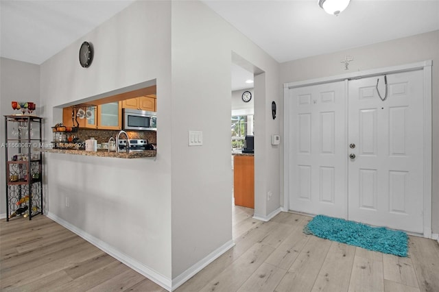 foyer entrance with light hardwood / wood-style floors and sink