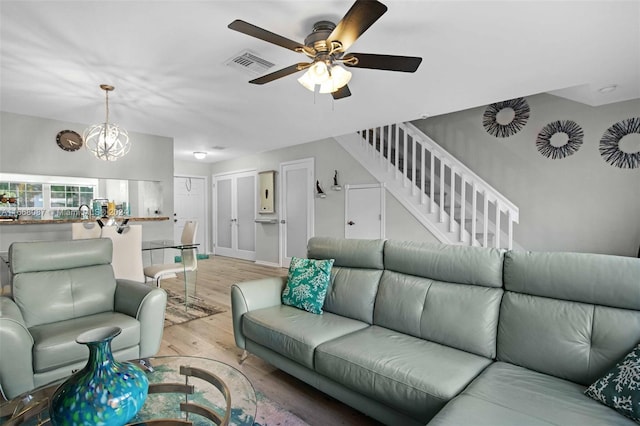 living room featuring ceiling fan with notable chandelier and light hardwood / wood-style floors