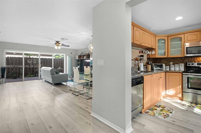 kitchen featuring dark stone counters, light hardwood / wood-style floors, appliances with stainless steel finishes, and ceiling fan